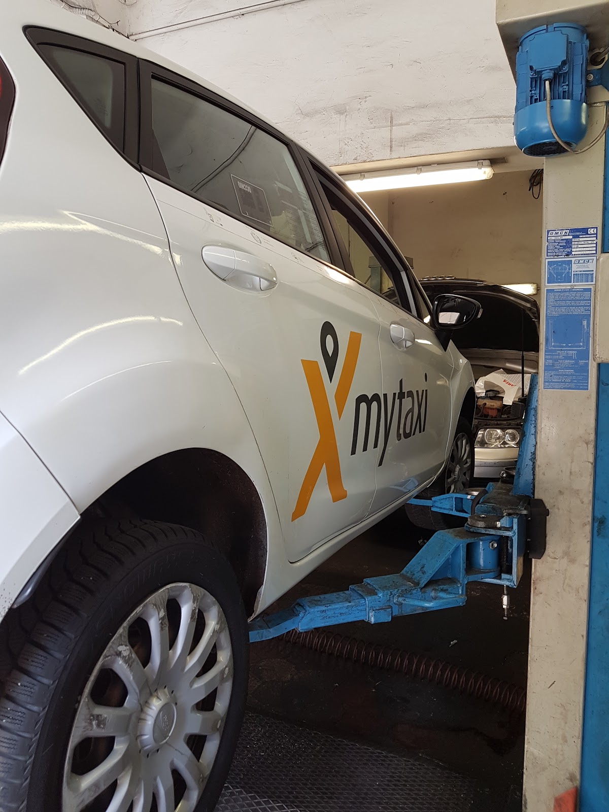 Auto MyTaxi in lavorazione su sollevatore OMCN blu